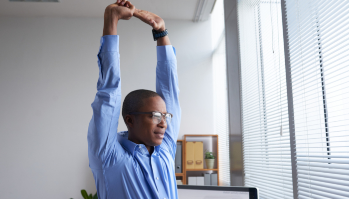 young-manager-doing-good-stretch-before-work-looking-window